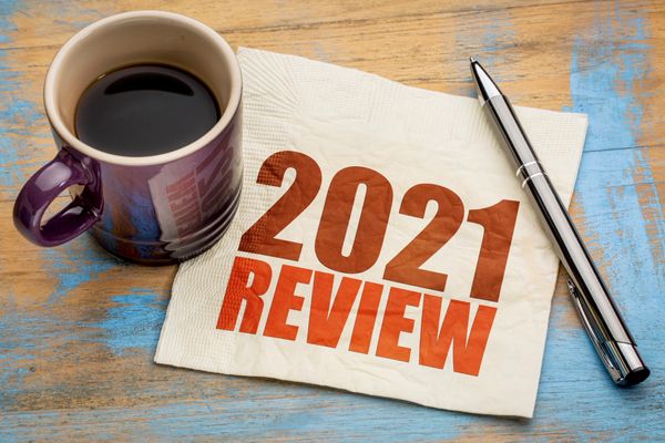 review of 2021 written on a napkin, alongside a cup of black coffee and a pen